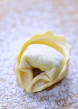 Preparing homemade tortellini on wooden table in the kitchen.