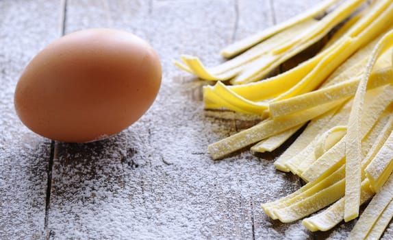 Preparing homemade tagliatelle on wooden table in the kitchen.