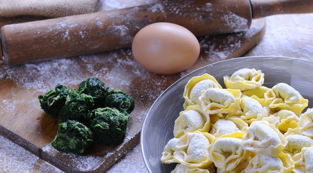 Preparing homemade tortellini on wooden table in the kitchen.