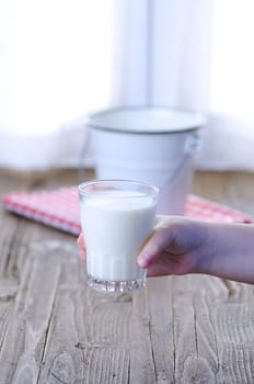 Glass of fresh milk on wooden table in the kitchen.