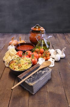 Cookbook on kitchen table with ingredients to cook pasta