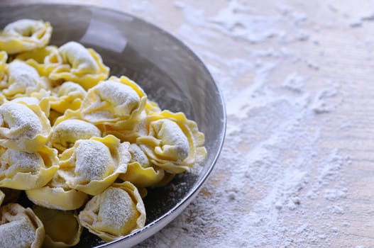 Preparing homemade tortellini on wooden table in the kitchen.