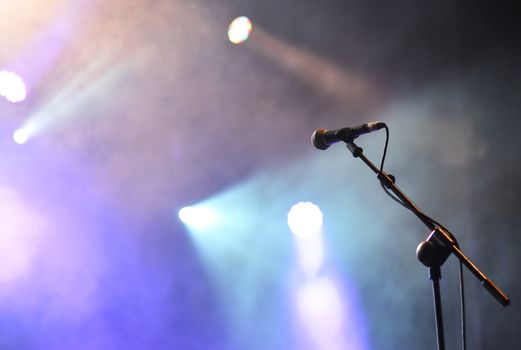 Microphone with spotlights with colored lights at a rock concert.