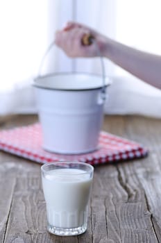 Glass of fresh milk on wooden table in the kitchen.