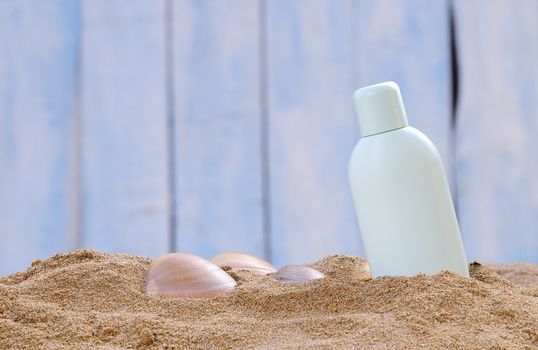 Jar of sunscreen on the beach sand.