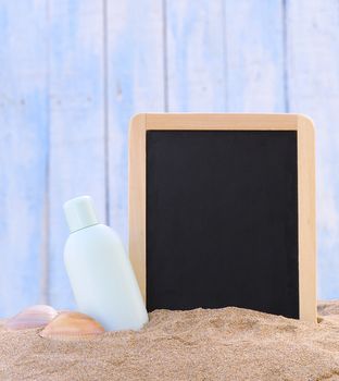 Jar of sunscreen on the beach sand and blackboard.