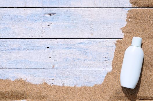Jar of sunscreen on the beach sand.