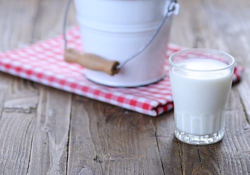 Glass of fresh milk on wooden table in the kitchen.