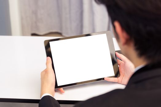 Work from home, Back view of Asian young businessman smile wearing suit video conference call or facetime by smart digital tablet computer blank screen on desk