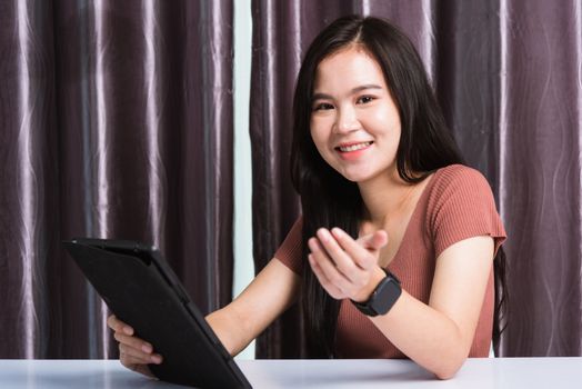 Work from home, Happy Asian business young beautiful woman sitting on desk workspace video call conferencing, write, check or read mail on digital tablet computer technology at home office