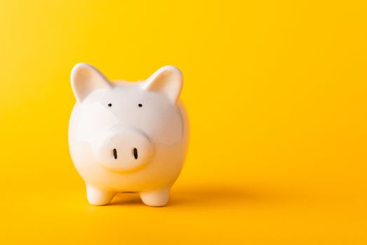 Front small white fat piggy bank, studio shot isolated on yellow background and copy space for use, Finance, deposit saving money concept