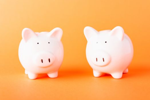 International Friendship Day, Front two small white fat piggy bank, studio shot isolated on orange background and copy space for use, Finance, deposit saving money concept