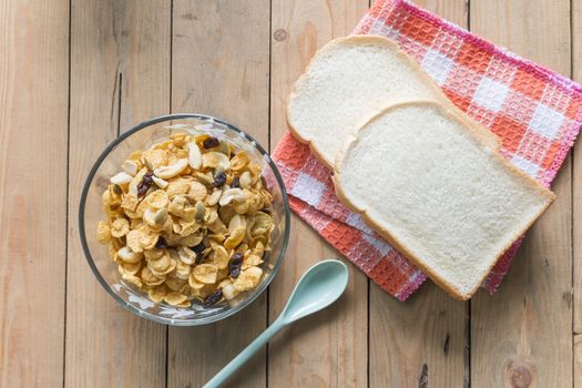 Corn flake in bowl with white bread on napkin on wooden table,top view,Breakfast