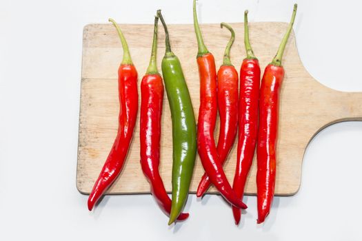 green chilli on red chilli on cutting board, different concept,food concept