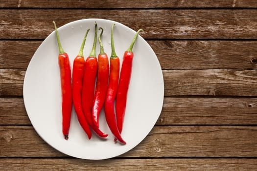 Red chilli pepper on white dish on wooden background,overhead,copy space for text