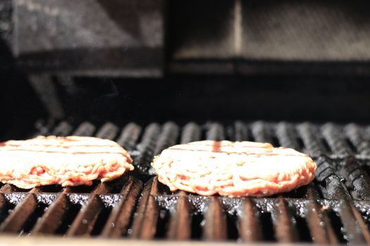 Raw burgers on bbq barbecue grill with fire. Food meat - raw burgers on bbq barbecue grill with fire. Shallow dof