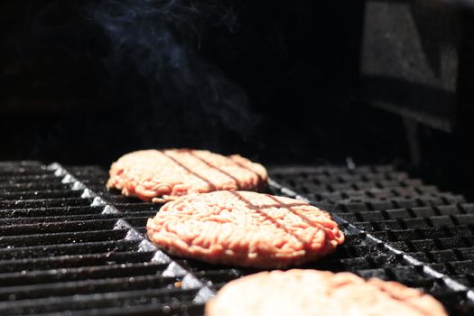 Raw burgers on bbq barbecue grill with fire. Food meat - raw burgers on bbq barbecue grill with fire. Shallow dof