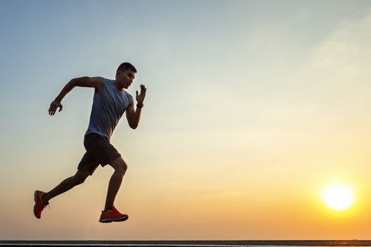 The silhouette of young men running and exercising at sunset with the sun in the background, colorful sunset sky