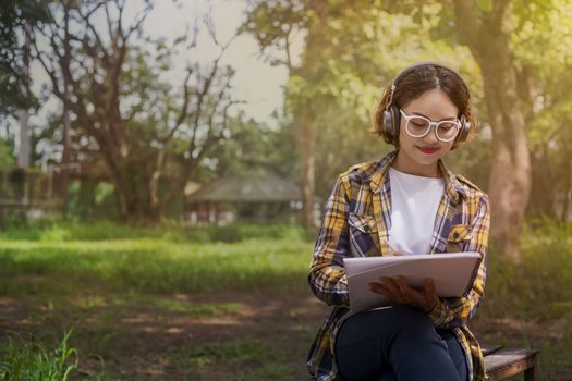 Beautiful woman listened to music while sitting happily on the lawn in the park.