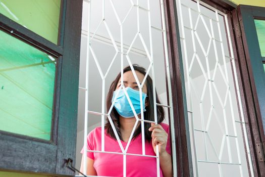 Corona virus (COVID-19), During detention at home Masked woman Feeling sad and lonely alone in the house Sometimes she uses her phone to make video calls to friends.