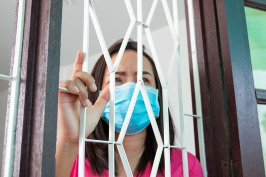 Corona virus (COVID-19), During detention at home Masked woman Feeling sad and lonely alone in the house Sometimes she uses her phone to make video calls to friends.