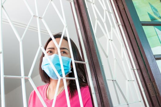 Corona virus (COVID-19), During detention at home Masked woman Feeling sad and lonely alone in the house Sometimes she uses her phone to make video calls to friends.