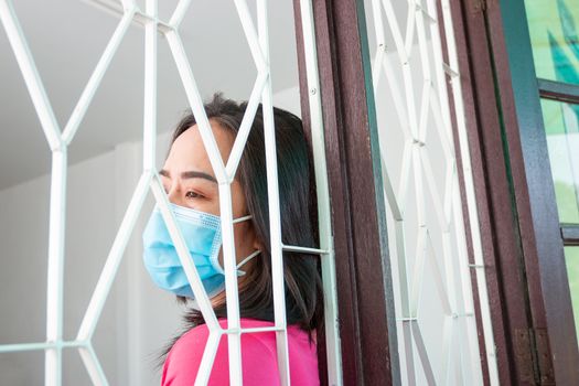 Corona virus (COVID-19), During detention at home Masked woman Feeling sad and lonely alone in the house Sometimes she uses her phone to make video calls to friends.