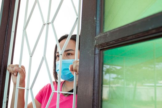 Corona virus (COVID-19), During detention at home Masked woman Feeling sad and lonely alone in the house Sometimes she uses her phone to make video calls to friends.