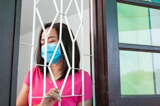 Corona virus (COVID-19), During detention at home Masked woman Feeling sad and lonely alone in the house Sometimes she uses her phone to make video calls to friends.