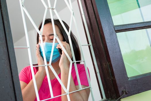 Corona virus (COVID-19), During detention at home Masked woman Feeling sad and lonely alone in the house Sometimes she uses her phone to make video calls to friends.