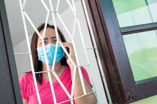Corona virus (COVID-19), During detention at home Masked woman Feeling sad and lonely alone in the house Sometimes she uses her phone to make video calls to friends.