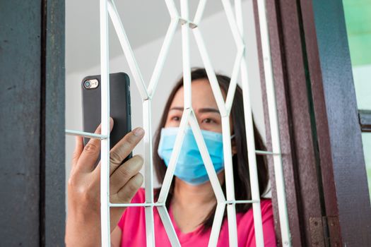 Corona virus (COVID-19), During detention at home Masked woman Feeling sad and lonely alone in the house Sometimes she uses her phone to make video calls to friends.
