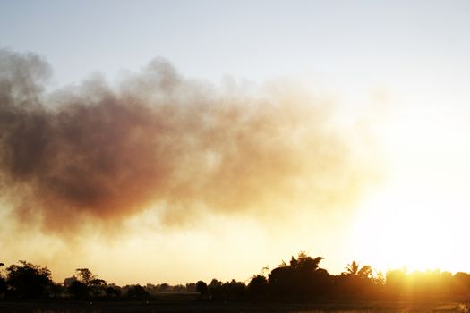 Many black smoke rise in the sky at sunset. The concept of weather is pollution.