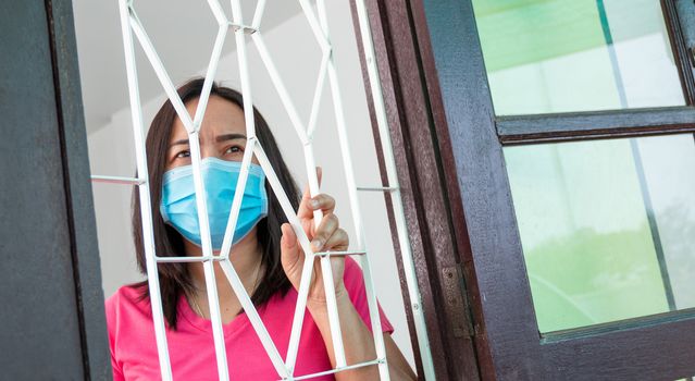 Corona virus (COVID-19), During detention at home Masked woman Feeling sad and lonely alone in the house Sometimes she uses her phone to make video calls to friends.