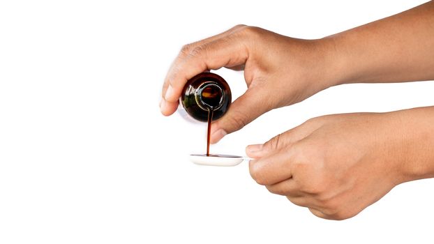 Pour the medicine into the spoon to feed the sick baby.