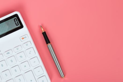 White calculator and pen on a bright pink background, marketing and financial concepts