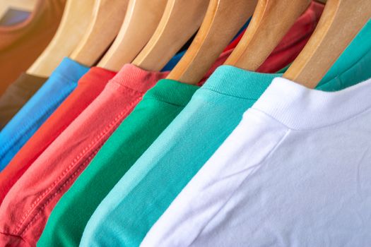 Fashion T-shirt on clothing rack - Closeup of bright colorful closet on wooden hangers in store closet