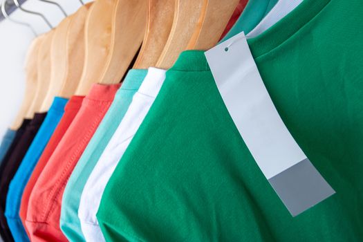 Fashion T-shirt on clothing rack - Closeup of bright colorful closet on wooden hangers in store closet