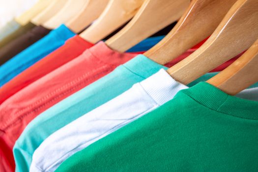 Fashion T-shirt on clothing rack - Closeup of bright colorful closet on wooden hangers in store closet