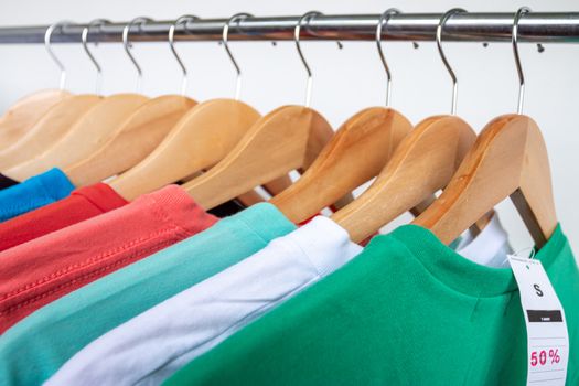 Fashion T-shirt on clothing rack - Closeup of bright colorful closet on wooden hangers in store closet