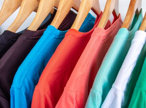 Fashion T-shirt on clothing rack - Closeup of bright colorful closet on wooden hangers in store closet