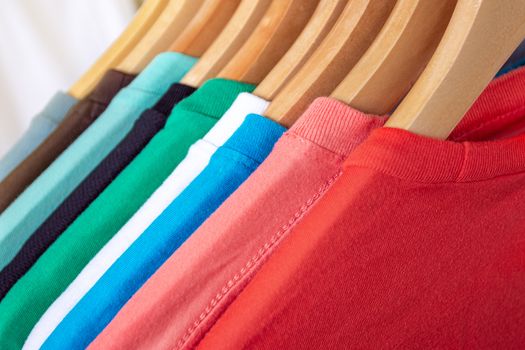 Fashion T-shirt on clothing rack - Closeup of bright colorful closet on wooden hangers in store closet