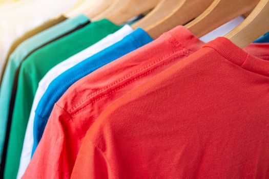 Fashion T-shirt on clothing rack - Closeup of bright colorful closet on wooden hangers in store closet