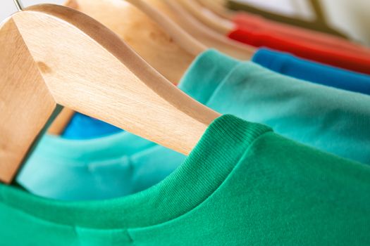 Fashion T-shirt on clothing rack - Closeup of bright colorful closet on wooden hangers in store closet