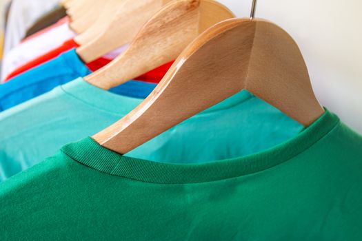 Fashion T-shirt on clothing rack - Closeup of bright colorful closet on wooden hangers in store closet