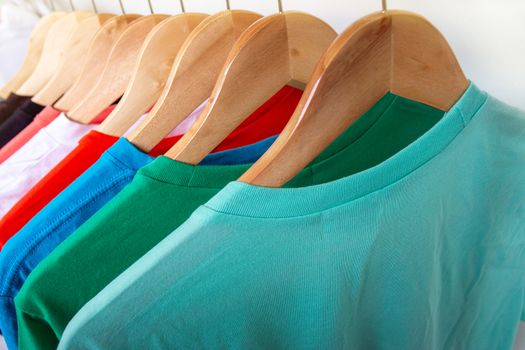 Fashion T-shirt on clothing rack - Closeup of bright colorful closet on wooden hangers in store closet