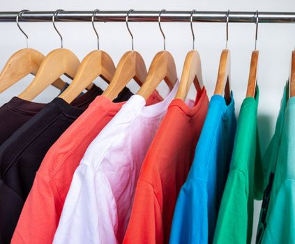 Fashion T-shirt on clothing rack - Closeup of bright colorful closet on wooden hangers in store closet