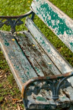 Old green wooden bench on green grass in lawn.