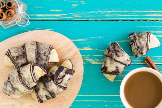 Croissant pastry with cup of coffee on vintage wooden background.