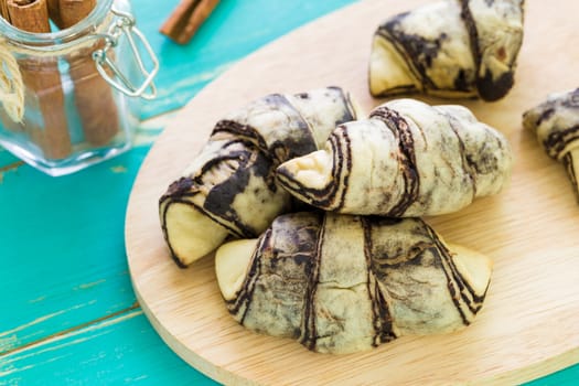Croissant bread with cinnamon on blue wooden background.